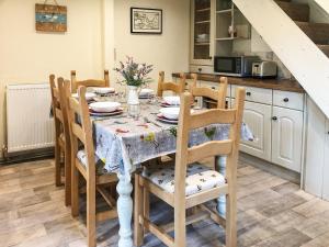 a dining room with a table and chairs and a kitchen at Beehive Cottage in Wittersham