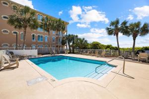a swimming pool in front of a building with palm trees at Tranquillity on 30A Unit# 210 by 30A Escapes in Seacrest