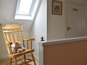 a teddy bear sitting in a wooden chair in a room at Tradewinds in Portknockie