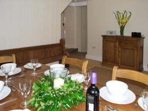 a dining room table with a bottle of wine and a table with glasses at Bank Cottage in Grindleford Bridge