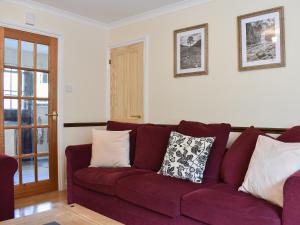 a living room with a red couch with pillows on it at Twizell Cottage in Alnwick