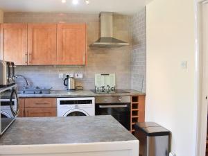 a kitchen with wooden cabinets and a stove top oven at Twizell Cottage in Alnwick +7 photos