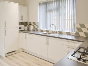 Una cocina con gabinetes blancos y un fregadero. en Forest Close, en Forest Hall