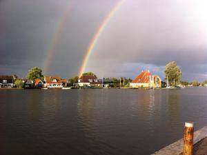 a rainbow over a lake with houses at Restful Holiday Home in Grou with Terrace and Garden in Grou