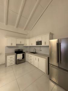 a kitchen with white cabinets and a stainless steel refrigerator at Apartamento dentro del campo de golf in Comayagua