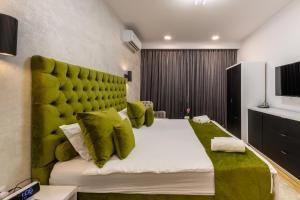 a bedroom with a large bed with a green headboard at Eden Central Boutique Suites - Garden & Spacious Apartments in Cluj-Napoca