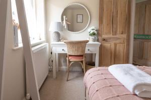 a bedroom with a desk with a chair and a mirror at The Lantern in Bourton on the Water