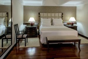 a bedroom with a large bed and two tables and a chair at Bourbon Hotel & Suites Curitiba in Curitiba +65 photos