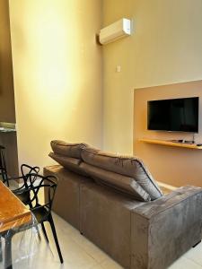 een woonkamer met een bank en een tv bij Studio Bougainville Apart in Conceição do Mato Dentro