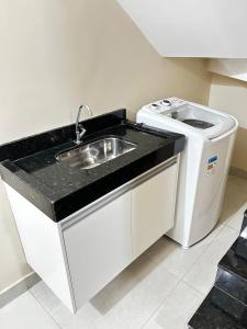 een keuken met een spoelbak en een wasmachine bij Studio Bougainville Apart in Conceição do Mato Dentro