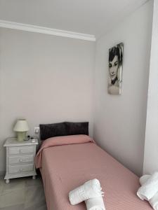 a bedroom with a bed with pink sheets and a nightstand at Apartamento Los Pajaritos II in Jerez de la Frontera