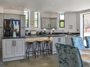 a kitchen with white cabinets and bar stools at St Mildred's Church in Ramsgate
