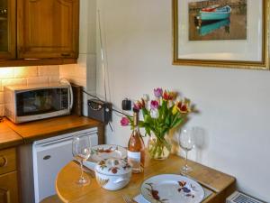 una cucina con tavolo, bicchieri da vino e fiori di Tilery Cottage - Uk44203 a Chatton