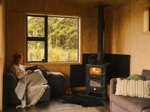 a woman sitting in a chair in a room with a wood stove at Beresford Heights & Rise in Maclennan