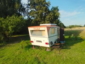 an rv parked in a field with two chairs at DDR Wohnwagen Friedel in Sandau