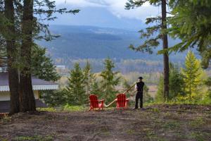 a man standing on a hill with two red chairs at Chalet Haesler Jr - Edelweiss Village in Golden