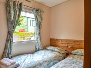 two beds in a bedroom with a window at The Beachcomber in Palnackie