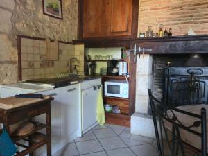 a small kitchen with a stove and a microwave at La Chataîgnière in Saint-Géry