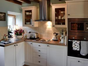 a kitchen with white cabinets and a stove top oven at Gwernol in Dolwyddelan