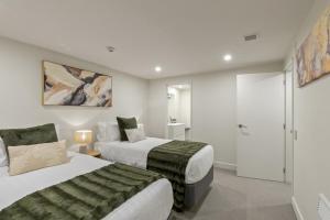 ein Hotelzimmer mit zwei Betten und einem Badezimmer in der Unterkunft Stunning Lakefront 2-bed 2-bath with lake views in Queenstown