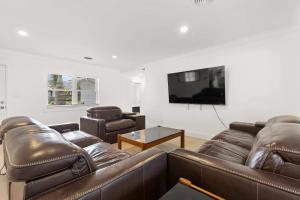 sala de estar con muebles de cuero y TV de pantalla plana en 3BR Waterfront Gem Pool Dog Friendly, en San Petersburgo