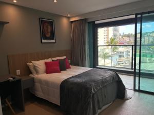 une chambre avec un grand lit et une grande fenêtre dans l'établissement Lindo studio frente mar!, à Salvador