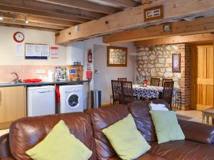 a living room with a leather couch and a kitchen at Gull Newk in Flamborough