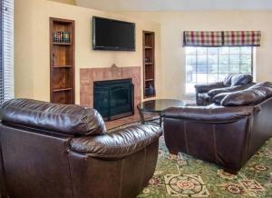 a living room with two leather chairs and a fireplace at Extended Studio Suites Hotel- Bossier City in Bossier City +13 photos
