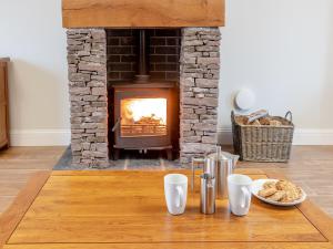 a living room with a fireplace with a table and a fire place at Iora Rua-Uk40006 in Gartmore
