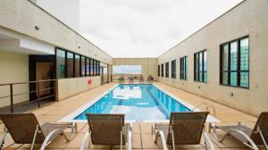 a swimming pool in a building with chairs around it at UH 406 - 3 Pessoas e garagem in Taguatinga