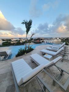 a group of lounge chairs and a swimming pool at Live Playa Beach, Luxury & 5th Av at your doorstep in Playa del Carmen