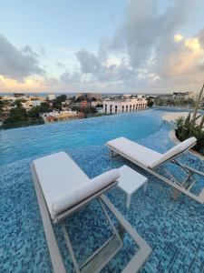 a pool with two lounge chairs and a table at Live Playa Beach, Luxury & 5th Av at your doorstep in Playa del Carmen