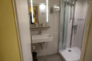 La salle de bains est pourvue d'un lavabo et d'une douche. dans l'établissement Hotel Villa Konstanz, à Berlin