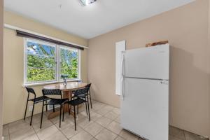 a kitchen with a table and a white refrigerator at Cozy Airb&b Guest Suite Near Metrotown in Burnaby