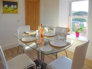 ein Esszimmer mit einem Glastisch und weißen Stühlen in der Unterkunft Charlies Cottage in Muasdale