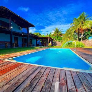 a pool with a wooden deck next to a house at Casa Tropical in Marau