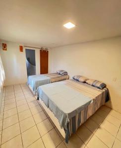 two beds in a room with a tiled floor at Casa Tropical in Marau