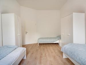 a white bedroom with two beds and a wooden floor at Breite Str 154 Selm in Selm +4 photos