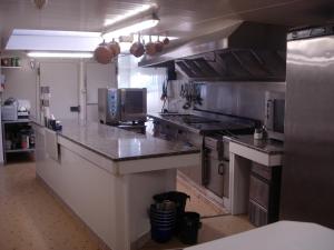 eine große Küche mit Arbeitsflächen aus Edelstahl und einer Arbeitsplatte in der Unterkunft La Grande Fontaine in Jugon Les Lacs