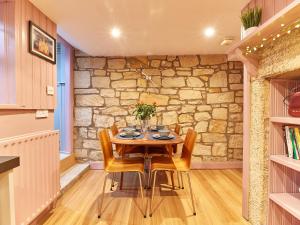 a dining room with a stone wall and a table and chairs at Alt-Na-Craig in Rothbury