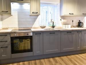 eine Küche mit grauen Schränken und einer Arbeitsplatte in der Unterkunft Low Quay Cottage in Conwy