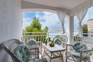 a porch with wicker chairs and a table on a balcony at Apartments with parking space Vidalici, Pag - 9393 in Kustići