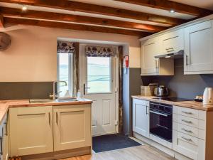 a kitchen with white cabinets and a sink at Trough Cottage - Uk48424 in Holmfirth
