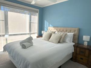 a bedroom with a large white bed with a window at Whitecaps Beachhouse - Pet Friendly on Easts Beach - Book 3 nights, pay 2 in Kiama