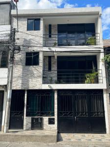 un bâtiment avec portes et fenêtres noires dans une rue dans l'établissement Primavera house - Habitaciones Full amobladas, à Ibagué