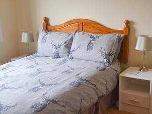 1 cama con edredón azul y blanco y 2 lámparas en The Junipers, en Tain