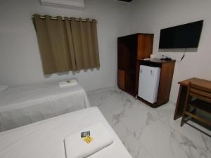 a room with a bed and a television and a table at Hotel Maringá in Juara