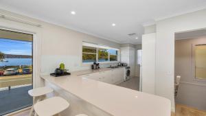 a kitchen with white counters and a large window at Ettalong Waterfront Retreat in Ettalong Beach