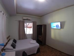 a bedroom with a bed and a tv on the wall at POUSADA EVELINA in Foz do Iguaçu