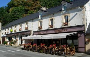 un bâtiment avec des tables et des chaises devant lui dans l'établissement La Grande Fontaine, à Jugon Les Lacs